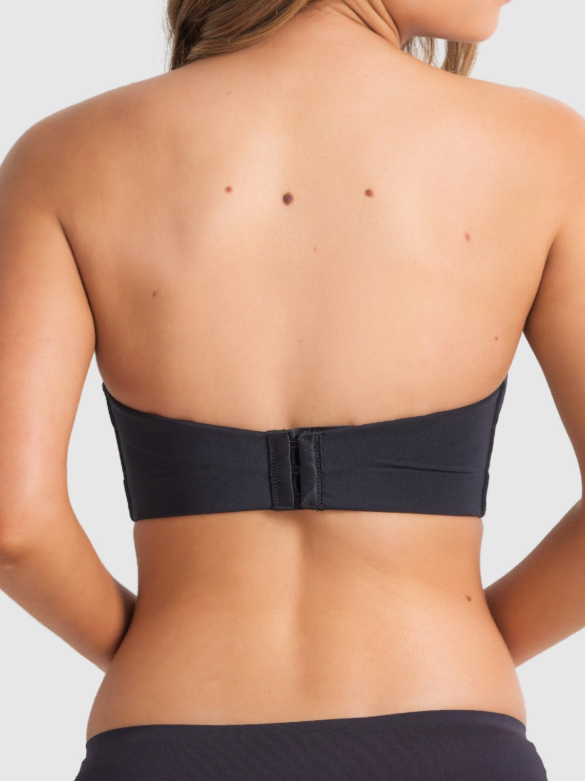 Back image of strapless black bra featuring sculpted band and hook-and-eye closure.