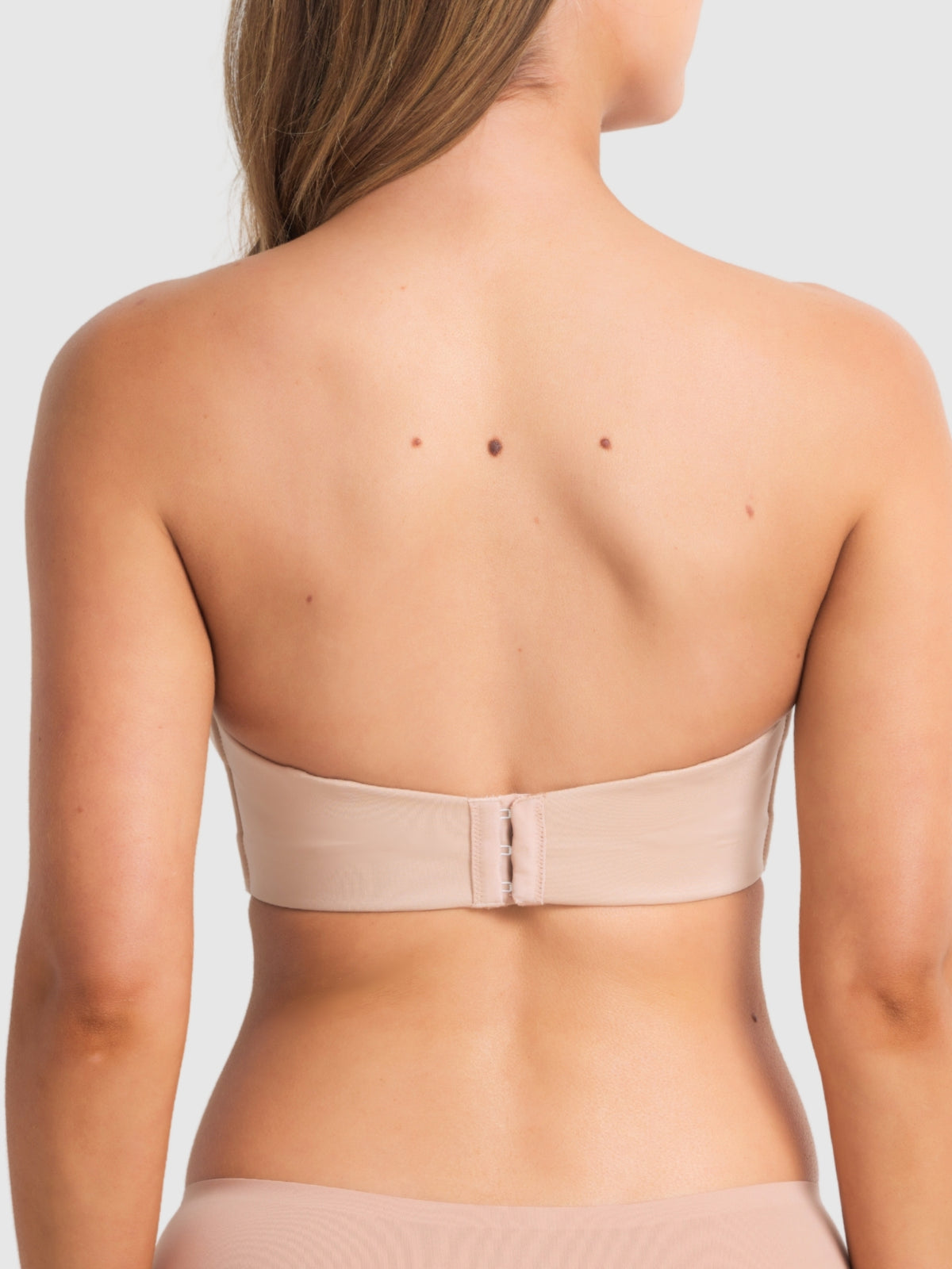 Back view of beige strapless bra showing smooth band and secure hook closure.