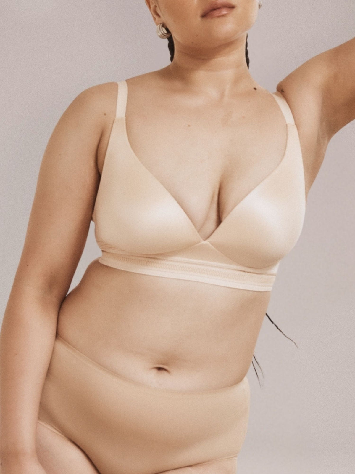 Woman wearing a beige wirefree bra and full brief set against a neutral background